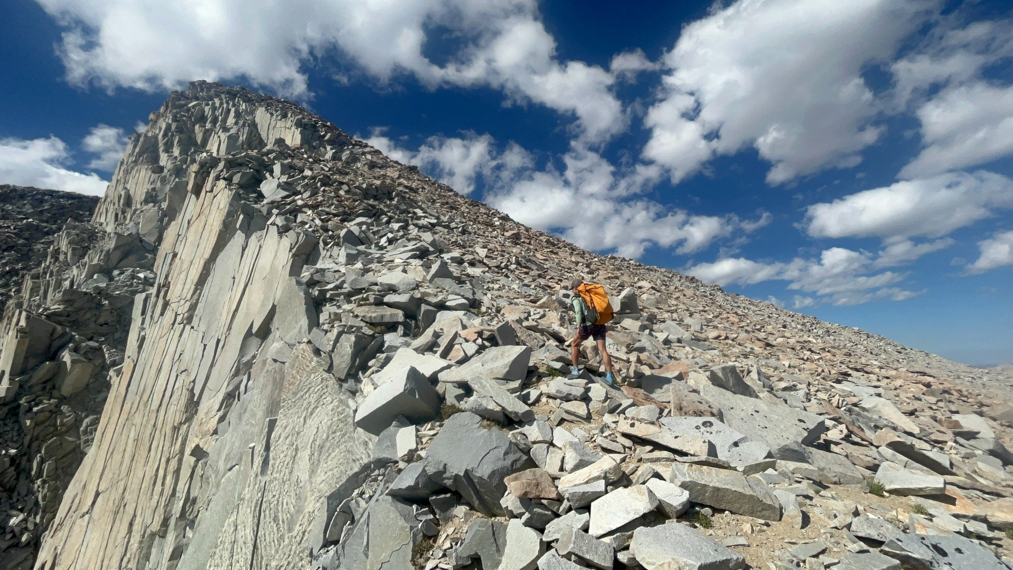 Backpacking across a rocky ridgeline beneath clouds